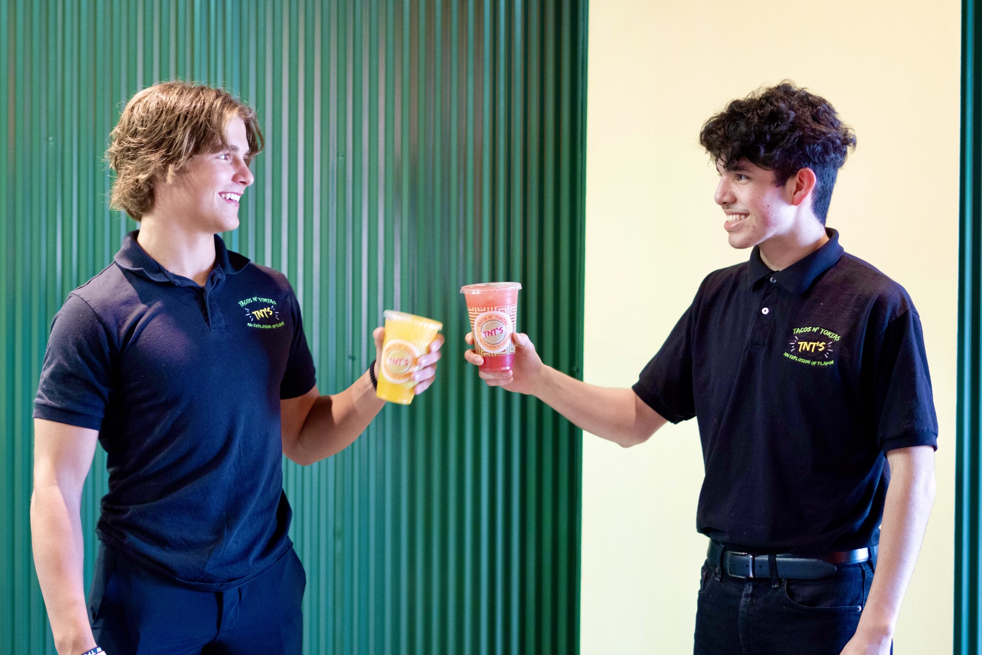 Two TNT’s team members smiling and holding colorful drinks