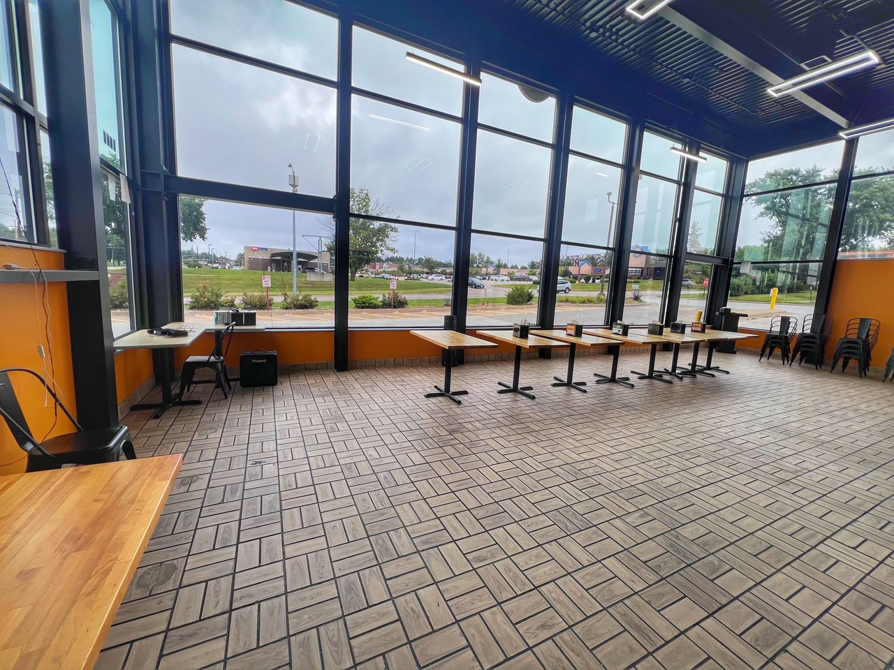 Large exterior windows and tables along the wall in TNT’s Urbandale Party Room