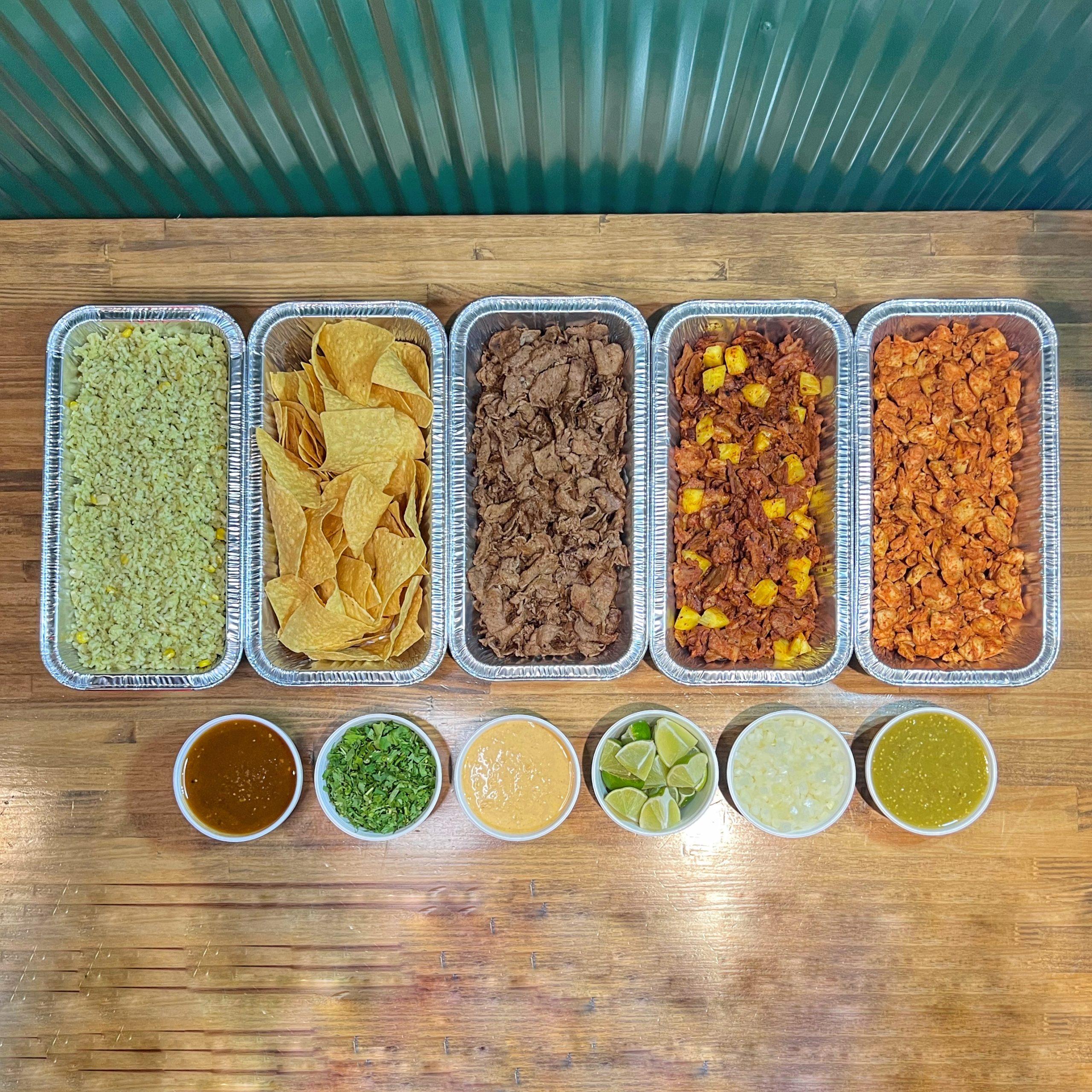 TNT’s Party Taco Bar spread with protein trays, chips and rice